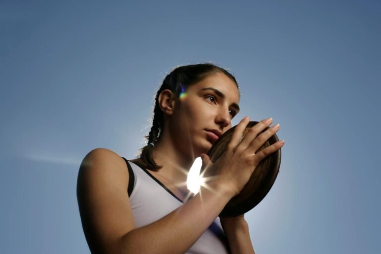 Eine Athletin hält einen Diskus, der von einem Sonnenstrahl umweht wird, der Stärke und Entschlossenheit symbolisiert.